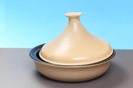 A new ceramic pan stands on a gray table and a blue background.の写真素材