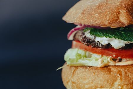 Burger flyer. Cheese burger with grilled meat, cheese, salad and onion rings. Close-up of delicious fresh home made burger  on bark blue backgroundの写真素材