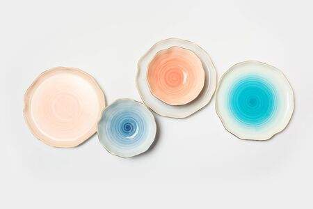 Varicolored ceramic plates and bowls on white backgroundの写真素材