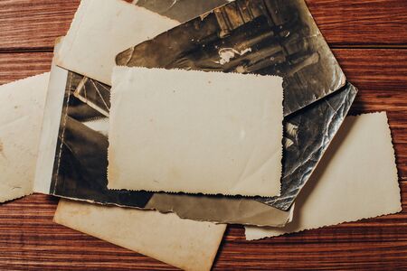 Stack old photos on table. Mock-up blank paper. Postcard rumpled and dirty vintage. Retro cardの写真素材