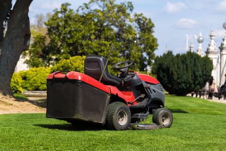 Old Lawn mower cutting green grass in backyard.Gardening background.の写真素材