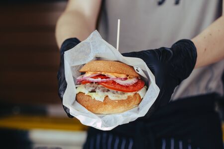 Cook preparing burger adding the sauce on the cream cheese. Three burgers.の写真素材