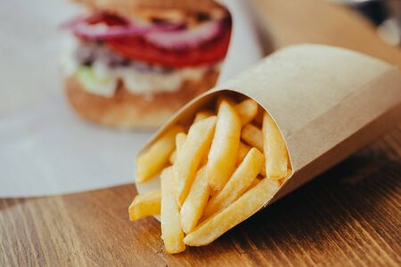 Fresh tasty burger and french fries on wooden table