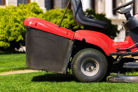 Old Lawn mower cutting green grass in backyard.Gardening background.
