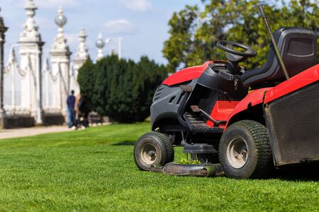 Old Lawn mower cutting green grass in backyard.Gardening background.