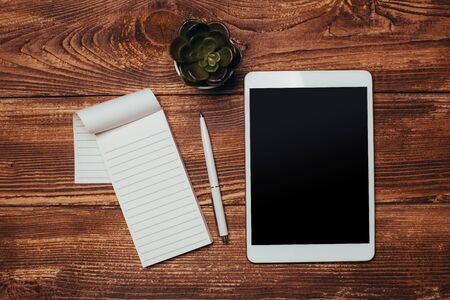 White digital tablet on wooden table. Flat lay.
