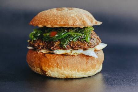 Burger flyer. Cheese burger with grilled meat, cheese, salad and onion rings. Close-up of delicious fresh home made burger  on bark blue backgroundの写真素材