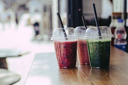 Sweet smoothie in plastic cups on wooden tableの写真素材