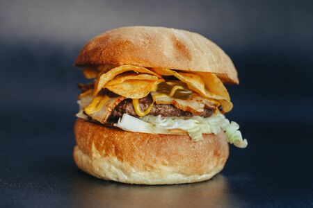 Burger flyer. Cheese burger with grilled meat, cheese, salad and onion rings. Close-up of delicious fresh home made burger  on bark blue backgroundの写真素材