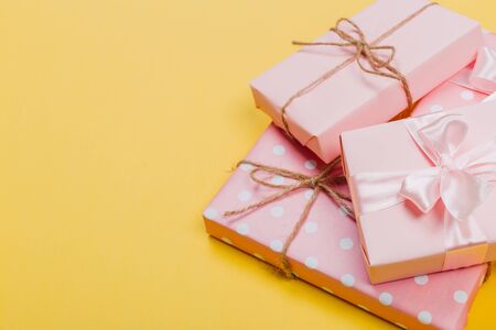 beautiful gift boxes wrapped in paper with red, gold and pink ribbon on a yellow surface. Top viewの写真素材