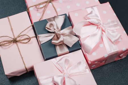 beautiful gift boxes wrapped in paper with red, gold and pink ribbon on a black surface. Top view