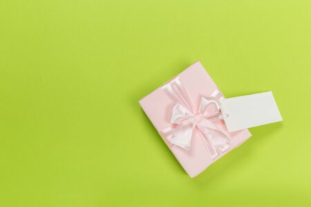Gift box wrapped in pastel  paper with pink ribbon on green surface. Top viewの写真素材