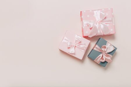beautiful gift boxes wrapped in paper with gold and pink ribbon on a beige surface. Top view with copy space.の写真素材