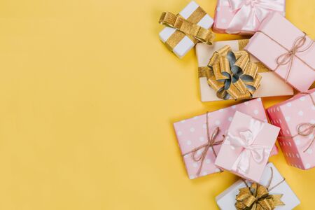beautiful gift boxes wrapped in paper with red, gold and pink ribbon on a yellow surface. Top viewの写真素材