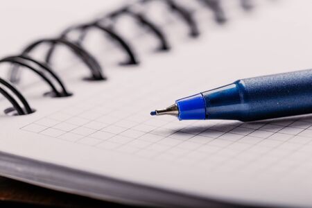 Opened notepad in a cage with an automatic plastic ballpoint pen close-up.