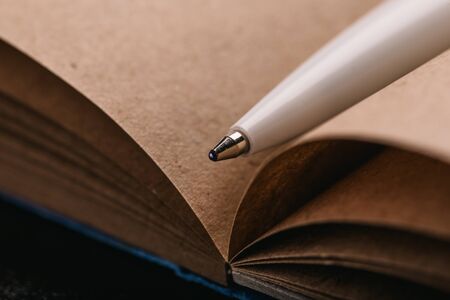 Opened notepad with automatic plastic ballpoint pen close up.