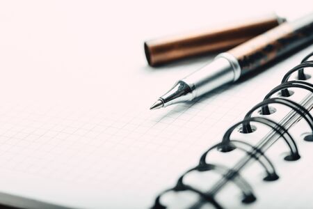 Opened notepad in a cage with an automatic plastic ballpoint pen close-up.の写真素材