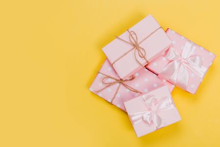 beautiful gift boxes wrapped in paper with red, gold and pink ribbon on a yellow surface. Top viewの写真素材