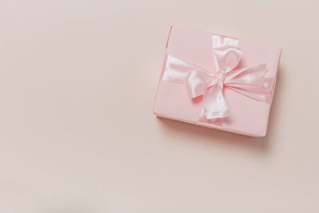 beautiful gift boxes wrapped in paper with gold and pink ribbon on a beige surface. Top view with copy space.の写真素材