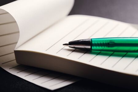 Opened notepad with automatic plastic ballpoint pen close up.
