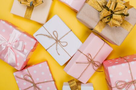 beautiful gift boxes wrapped in paper with red, gold and pink ribbon on a yellow surface. Top viewの写真素材