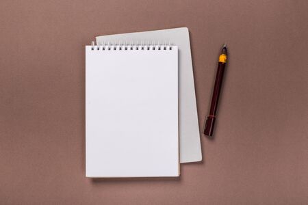 school notepad and pen on the brown desk. spiral notepad on a tableの写真素材