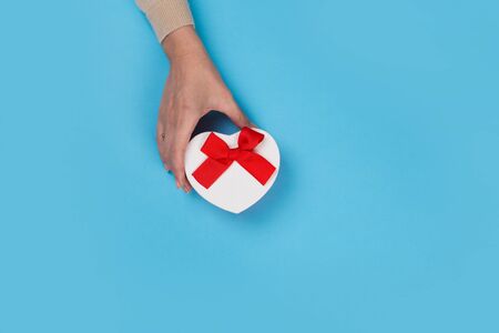Womans hands holding gift or present box on blue pastel table top view. Flat lay  for birthday or New Year.の写真素材