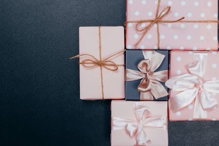 beautiful gift boxes wrapped in paper with red, gold and pink ribbon on a black surface. Top viewの写真素材