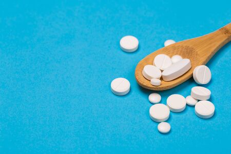 Assorted pharmaceutical medicine pills, tablets and capsules on wooden spoon