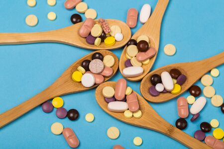 Assorted pharmaceutical medicine pills, tablets and capsules on wooden spoonの写真素材