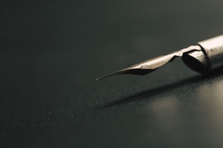 Old fountain pen on a black textured background