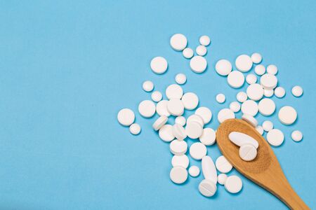 Assorted pharmaceutical medicine pills, tablets and capsules on wooden spoon