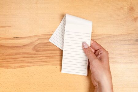 Woman hand holding blank paper on wooden background.の写真素材