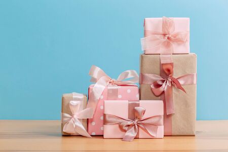 set of beautiful different gift boxes made by handmade with pink bows on a wooden table with a blue...