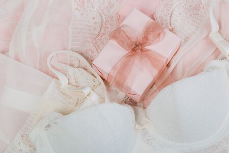 White women underwear with lace and gift box on beige background. white bra and pantie.Copy space. Beauty, fashion blogger concept. Romantic lingerie for Valentine's day temptation.の写真素材