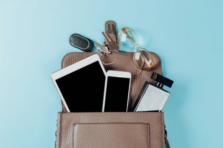 Fashion concept : Flat lay of brown leather woman bag open out with cosmetics, accessories and smartphone on pink backgroundの写真素材