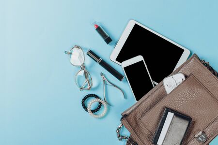 Fashion concept : Flat lay of brown leather woman bag open out with cosmetics, accessories and smartphone on pink backgroundの写真素材