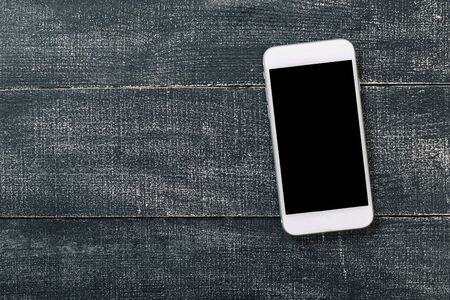 White mobile phone on an office working dark wooden table.の写真素材