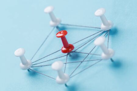 Small network of pins (Thumbtack)and string, An arrangement of colorful pins linked together with string on a pale blue background suggesting a network of connections.の写真素材