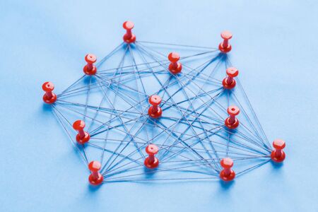 Small network of pins (Thumbtack)and string, An arrangement of colorful pins linked together with string on a pale blue background suggesting a network of connections.の写真素材