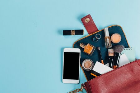Fashion concept : Flat lay of brown leather woman bag open out with cosmetics, accessories and smartphone on pink backgroundの写真素材