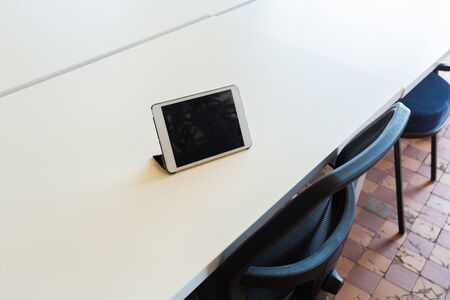 Loft style office with white brick walls and concrete columns. There is a meeting area with a large white table with black chairsの写真素材