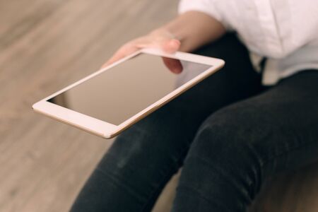 Mockup image of a woman sitting and holding white tablet pc with blank desktop screenの写真素材