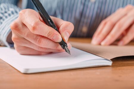 Beautiful Female hands write pen in a notebook of tasks and goals to work on a  tableの写真素材