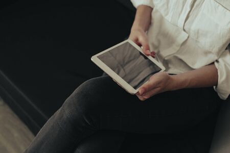 Mockup image of a woman sitting and holding white tablet pc with blank desktop screen 