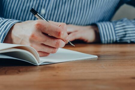 Beautiful Female hands write pen in a notebook of tasks and goals to work on a  table