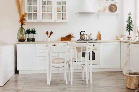 Modern new bright kitchen interior with white furniture and a dining table.の写真素材