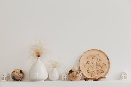 Neutral vases and plates on a white shelf against rough stucco of a gray wall. Home decor.の写真素材