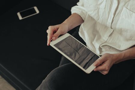 Mockup image of a woman sitting and holding white tablet pc with blank desktop screen 