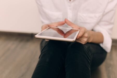 Mockup image of a woman sitting and holding white tablet pc with blank desktop screenの写真素材
